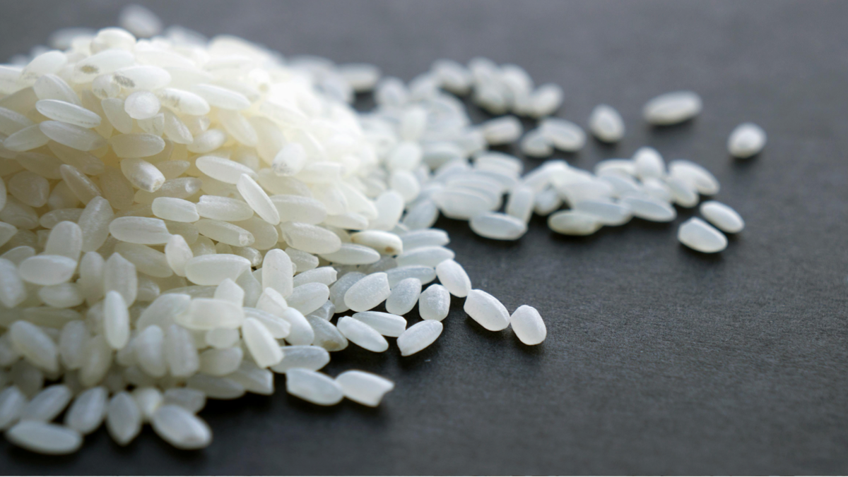 Bowl of basmati rice with separate grains served next to grilled chicken.