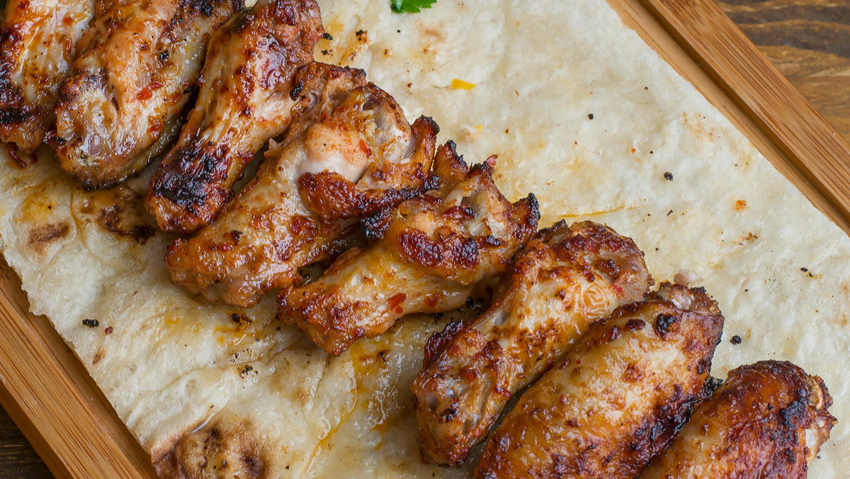 Lava charcoal chicken wings with golden blistered skin served with sauces