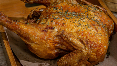 Whole rotisserie chicken roasting over gas flame