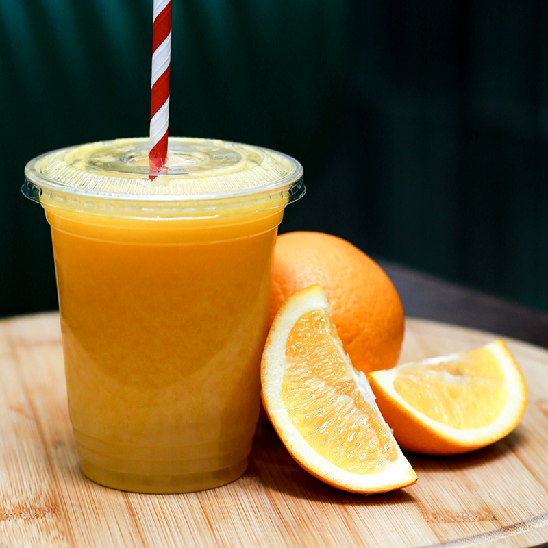Glass of orange juice beside halved oranges